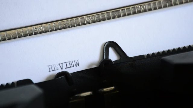 Typing the word REVIEW with an old manual typewriter