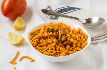 Indian fried snack, namkeen with peanuts, peas, lemon, tomato on white background