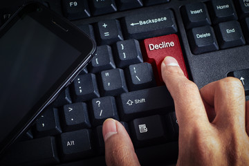 business concept shows the smartphone as well as the fingers that press DECLINE on the keyboard