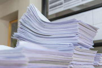 documents on desk stack up high waiting to be managed