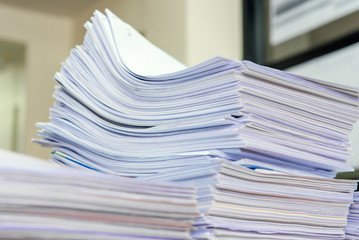 documents on desk stack up high waiting to be managed