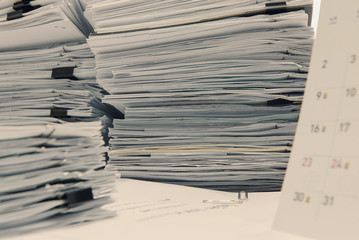 documents on desk stack up high waiting to be managed