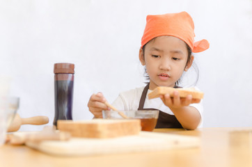 Asian little girl hold the bread and honey dipper stick on white