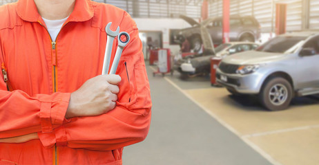 Mechanic holding wrench in car garage, Mechanic and tools concept.