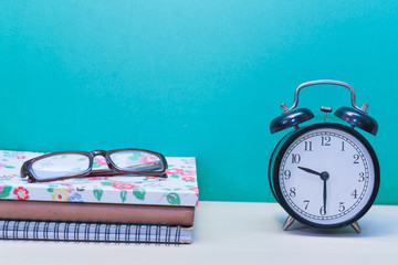 Alarm clock,glasses and Books on wooden table with copy space.Green background.