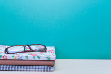 Books and glasses on wooden table with copy space.Green background.