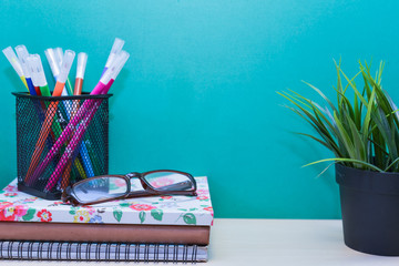 Green Plant,Books,color pens and glasses on wooden table with copy space.Green background.