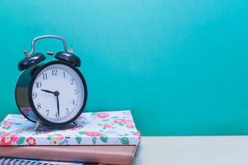 Alarm clock andBooks on wooden table with copy space.Green background.