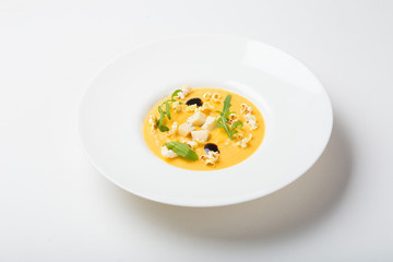 cream soup with popcorn, arugula on white background