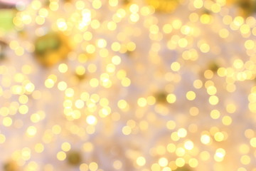 Golden ball ornament, bokeh lights on white Christmas tree blurred