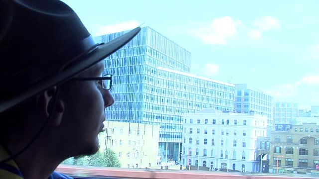 Man with hat looking the city out the window