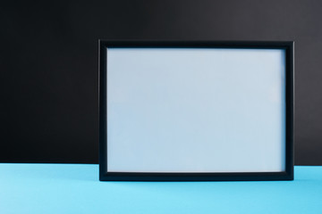 empty modern style frame on blue table against dark background