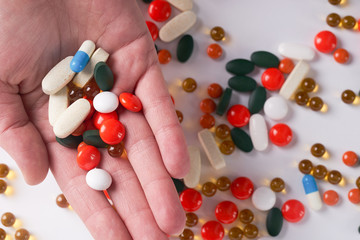 Hands holds different colored medicine and types of pills