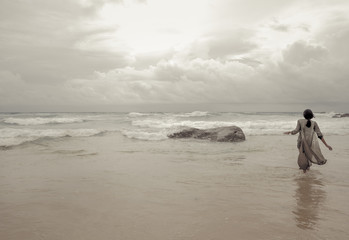 Elegant woman walking alone in the sea attracted by the divine light of sky, in front of amazing...