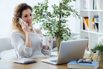 Obraz premium Beautiful young woman using her mobile phone in the office.