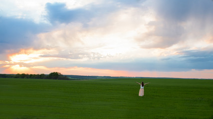 Girl, sunset, field, sky, clouds concept of freedom and nature