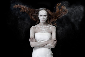Art portrait of a Beautiful girl covered in white dust over black background