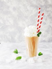 pink milkshake with ice cubes and mint leaves on a marble table, selective focus