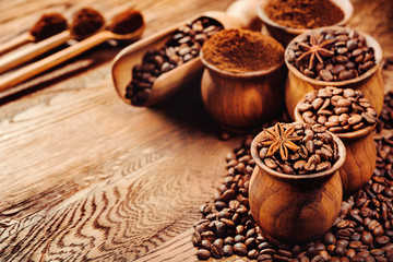 Сoffee beans in wooden pots and scoops on wooden background