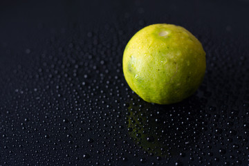 Fototapeta na wymiar Fresh lime with Water drops on black glass background