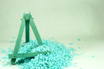Blue wooden easel, which is filled with small blue stones.