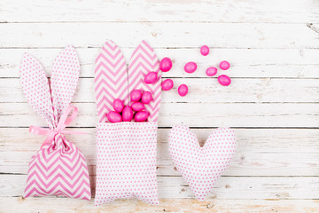 Bunny treat bag with pink candy.; Easter concept on wood background