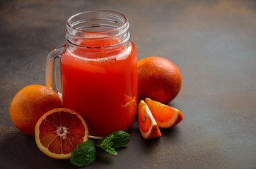 Fresh blood orange juice in mason jar on dark background, selective focus, copy space