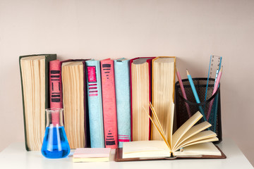 Open book, stack of colorful hardback books on light table. Back to school. Copy space for text