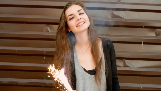 Young woman dancing with sparkler in the street, slow motion shot, retro color