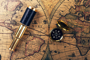 Fototapeta na wymiar vintage compass and spyglass on ancient world map