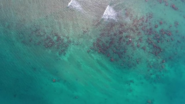 Top view aerial video of sea waves in shallow water with stones, 4k

