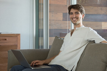 Jeune homme travaillant sur son canapé