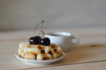 Waffles, cherry and coffee on the wooden table
