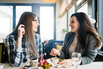 Two happy friends coffee talk in coffee shop