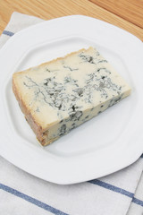 Fetta di gorgonzola su piatto su tavolo di legno