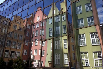 Fototapeta premium Colorful tenement houses reflected in windows of modern building