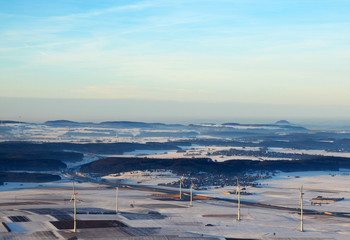 Aerial view  of wind turbines and german highway  in snowy southern germany on a sunny winter day (south of the swabian alps)