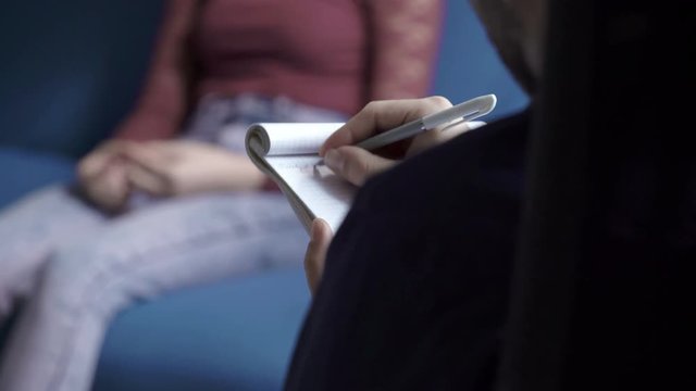 psychologist takes notes during therapy session
