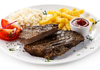 Grilled steaks, French fries and vegetables