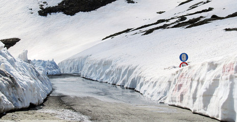 Road of Passo di Gavia, a high mountain pass in Italian Alps  with covered road sign (Snow Tires Required)