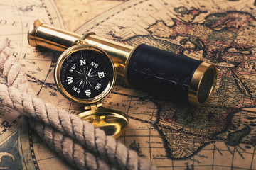 Fototapeta na wymiar adventures concept - vintage compass and spyglass on old world map