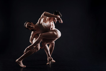 Fototapeta na wymiar Flexible gymnasts performing in the black colored studio