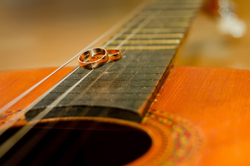 Wedding rings lying on the strings of a guitar