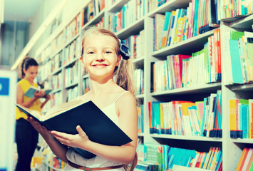 Small girl in school age standing with open book