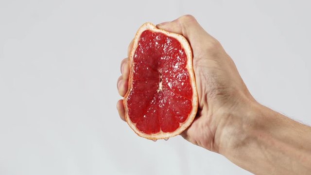 Grapefruit, hand squeezes out juice closeup