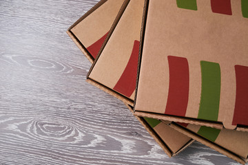 Stack of cardboard pizza boxes on wooden background.Top view with copy space.