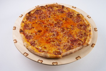 Delicious hot pizza with pepperoni - thin pastry crust at wooden round desk isolated at white background.