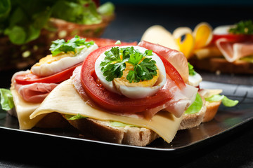 Delicious sandwich with prosciutto ham, cheese, tomato and egg