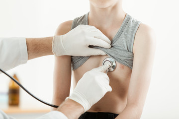 Doctor listening boys chest