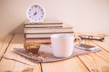 Working wood table with notebook glasses coffee mug clock and bo
